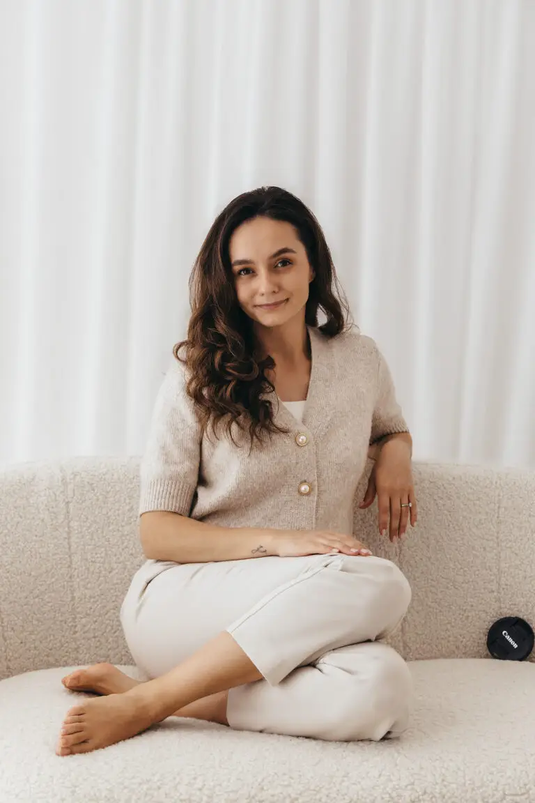 woman sitting on a white sofa in a white photography studio