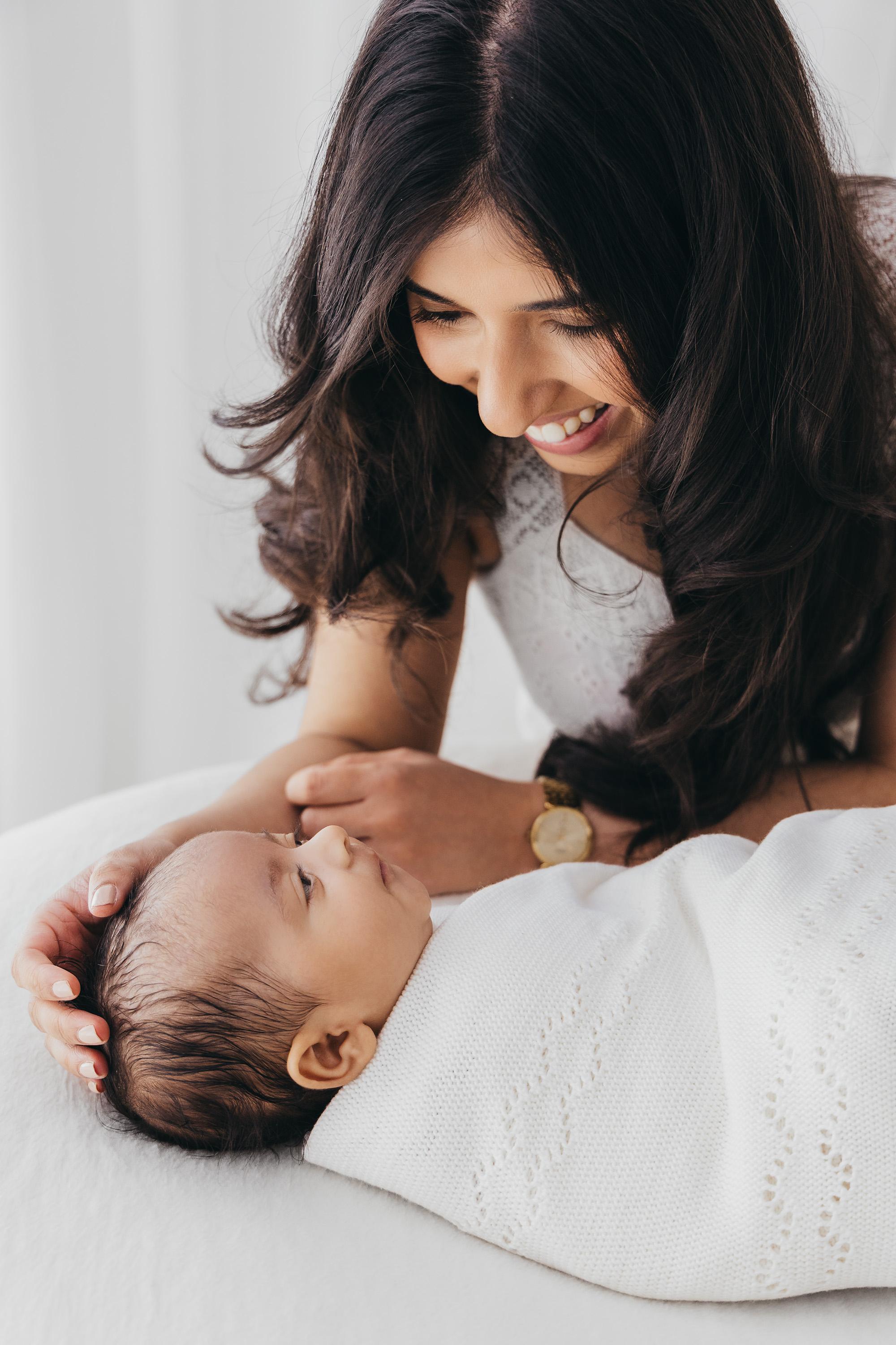 Parents leaning over their sleeping newborn baby during a natural photoshoot at Oana Maria Photography in Rugby