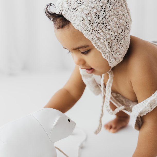 baby portrait playing with toy in bright white studio